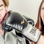 Woman mock-punching man with boxing gloves